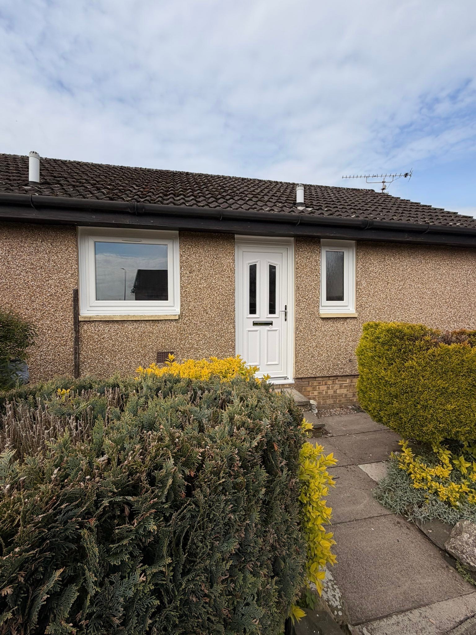 Front of a pebble-dashed bungalow in Dundee with its new white replacement windows